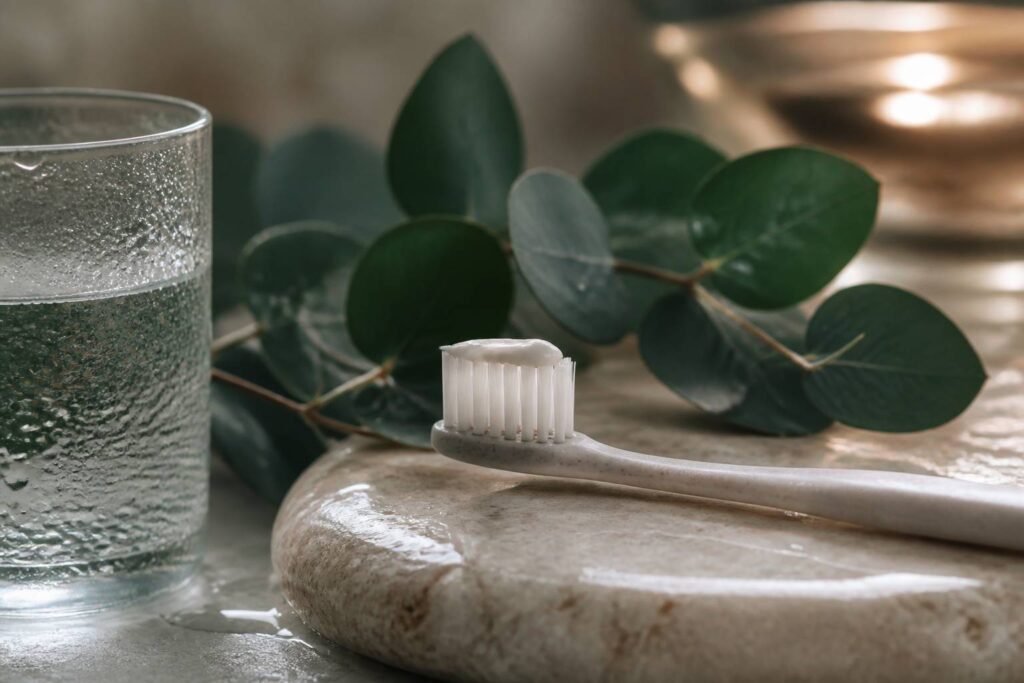 Brosse à dents avec dentifrice blanc sur pierre et eucalyptus