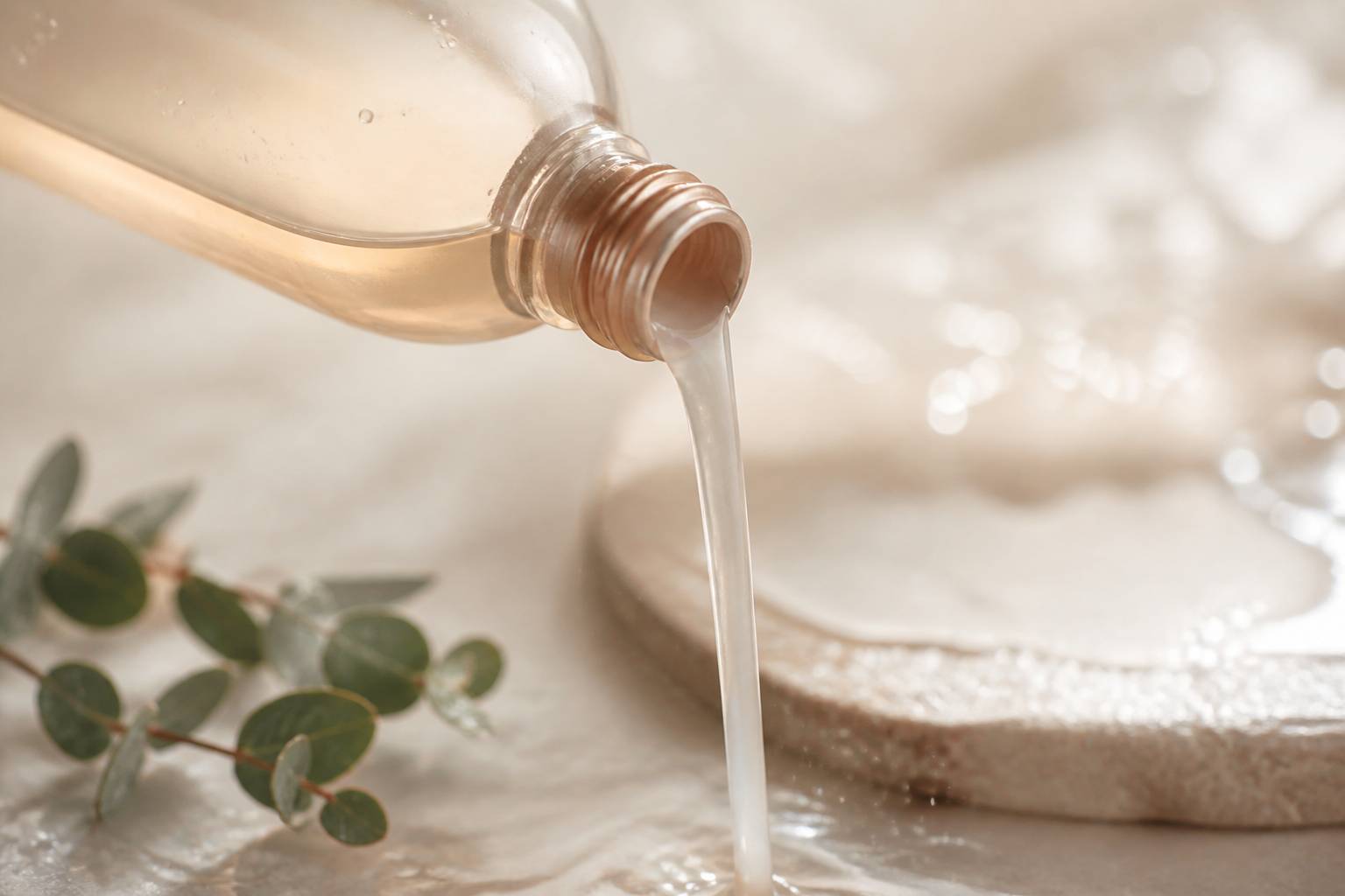 Coulée laiteuse d'huile de douche nacrée avec gouttelettes