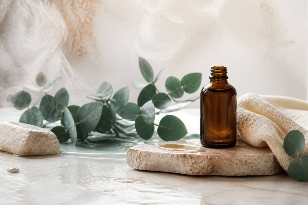 Flacon en verre ambré posé sur une pierre avec eucalyptus