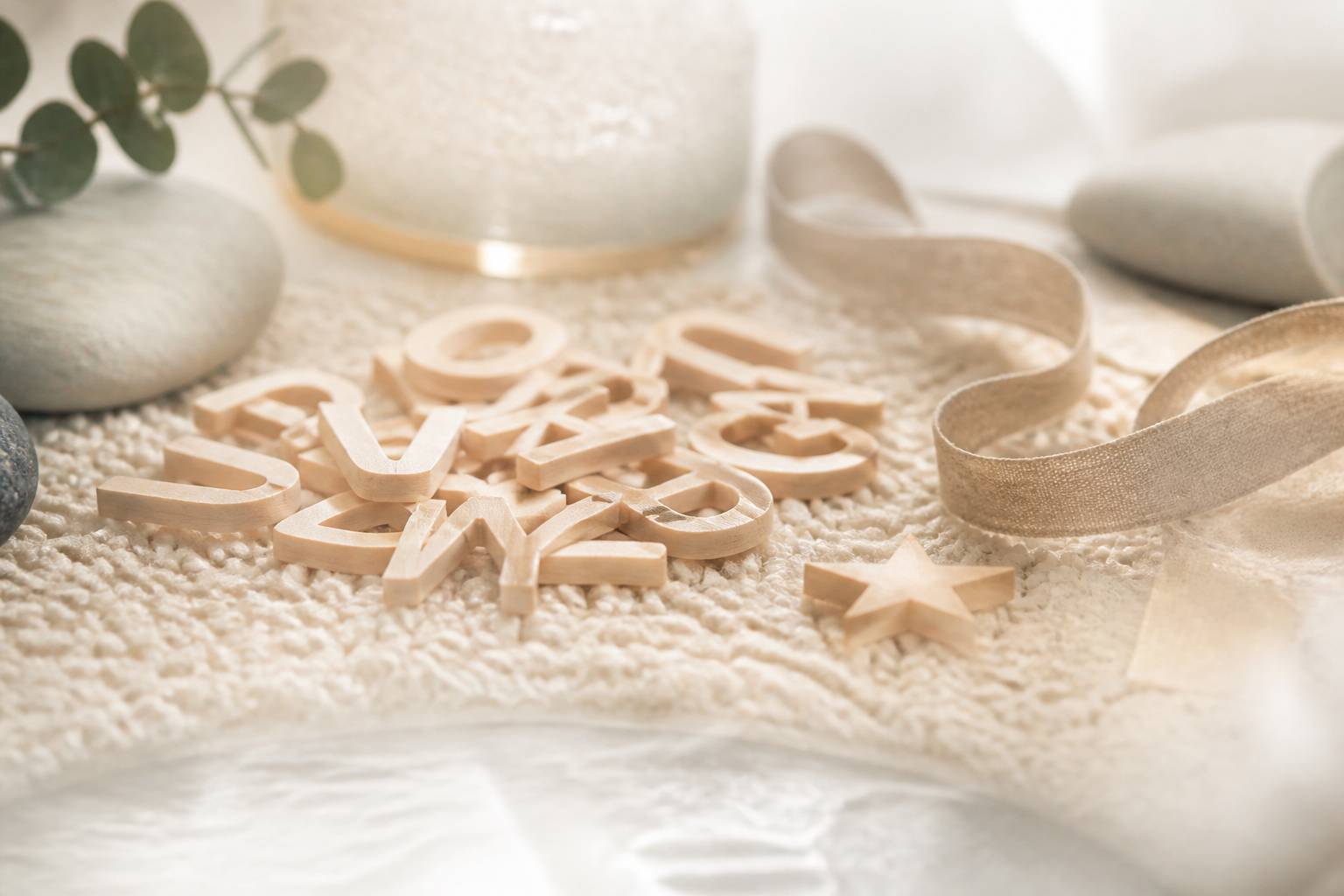Lettres en bois clair eparpillees sur un tapis de laine creme
