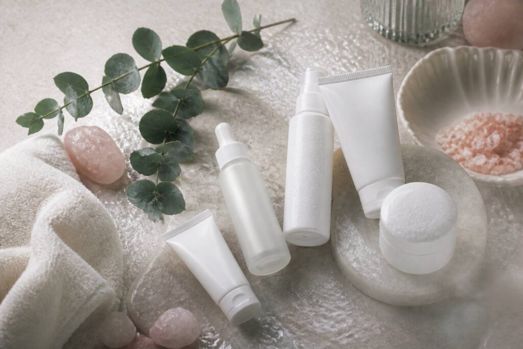 Flat-lay de flacons blancs sans étiquette avec serviette ivoire et eucalyptus
