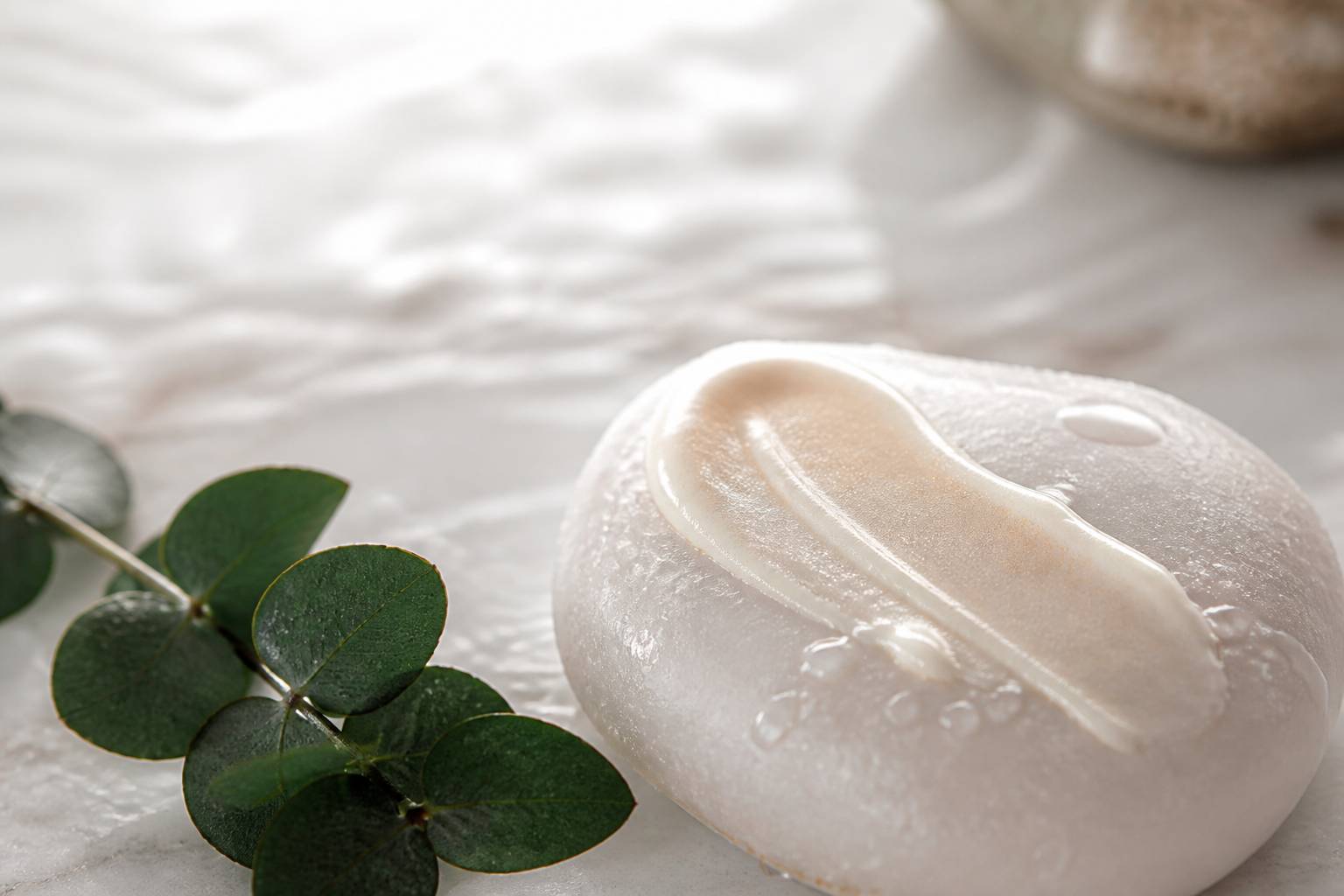 Texture nacrée de soin appliquée sur une pierre avec gouttes d'eau